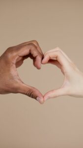 The hands of a black person and a white person forming a heart, illustrating anti-racism.