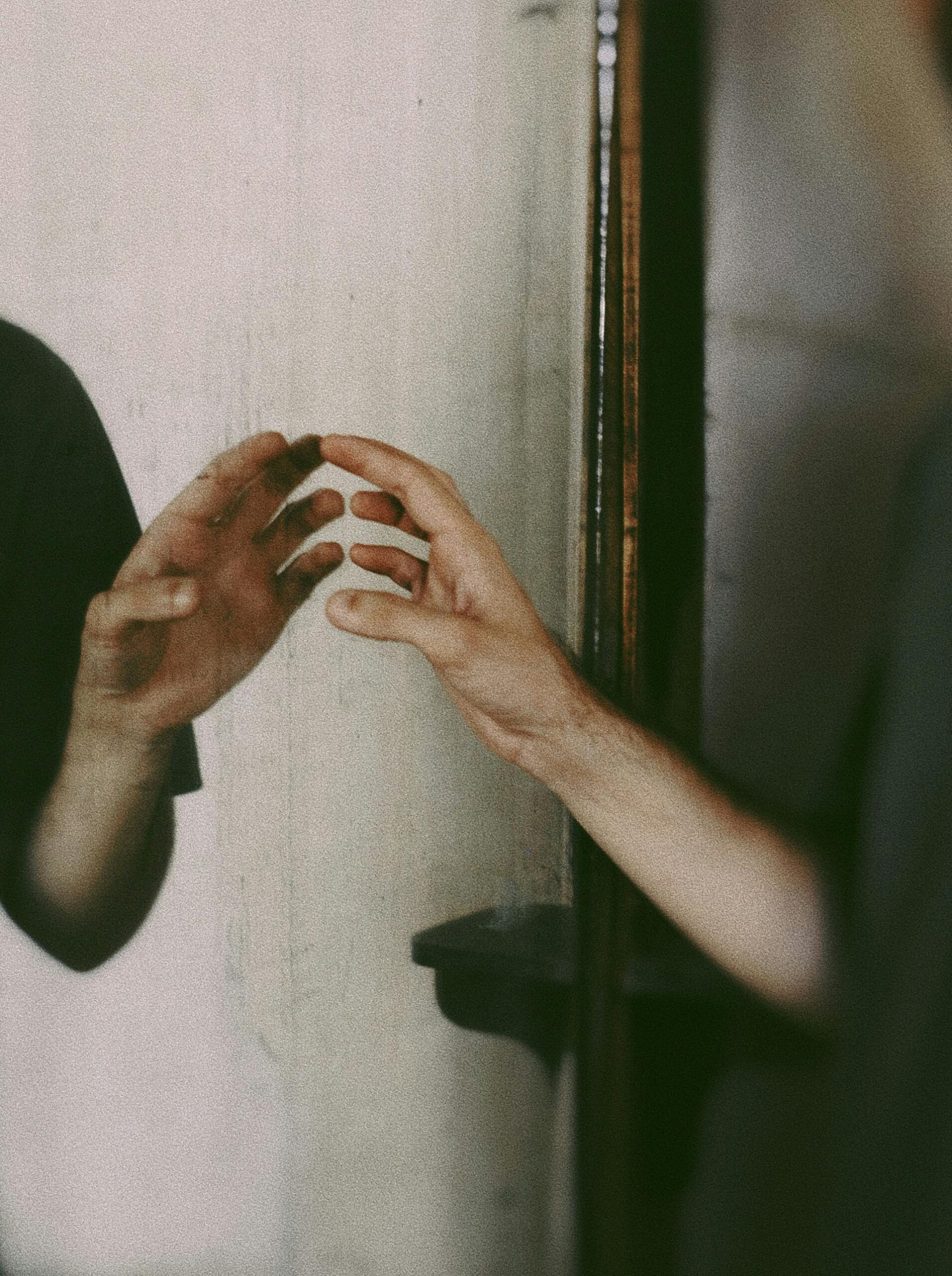 A hand reaching for its reflection, representing the journey of quieting the inner critic and healing from autistic RSD.