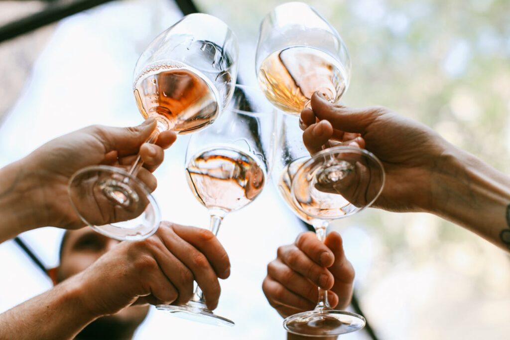 The hands of friends clinking glasses together in a toast symbolising genuine and supportive connection.