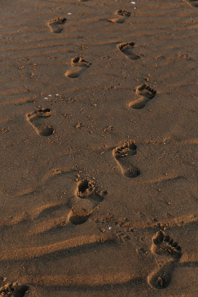 Footprints in the sand, symbolising the journey of recovery and the decision to tread lightly after burnout.